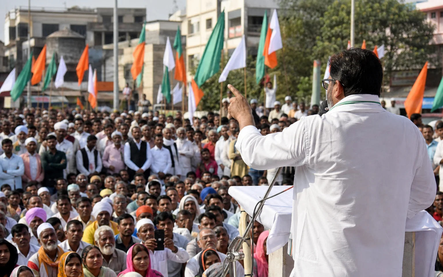A daytime public gathering around an outdoor stage in an Indian city square